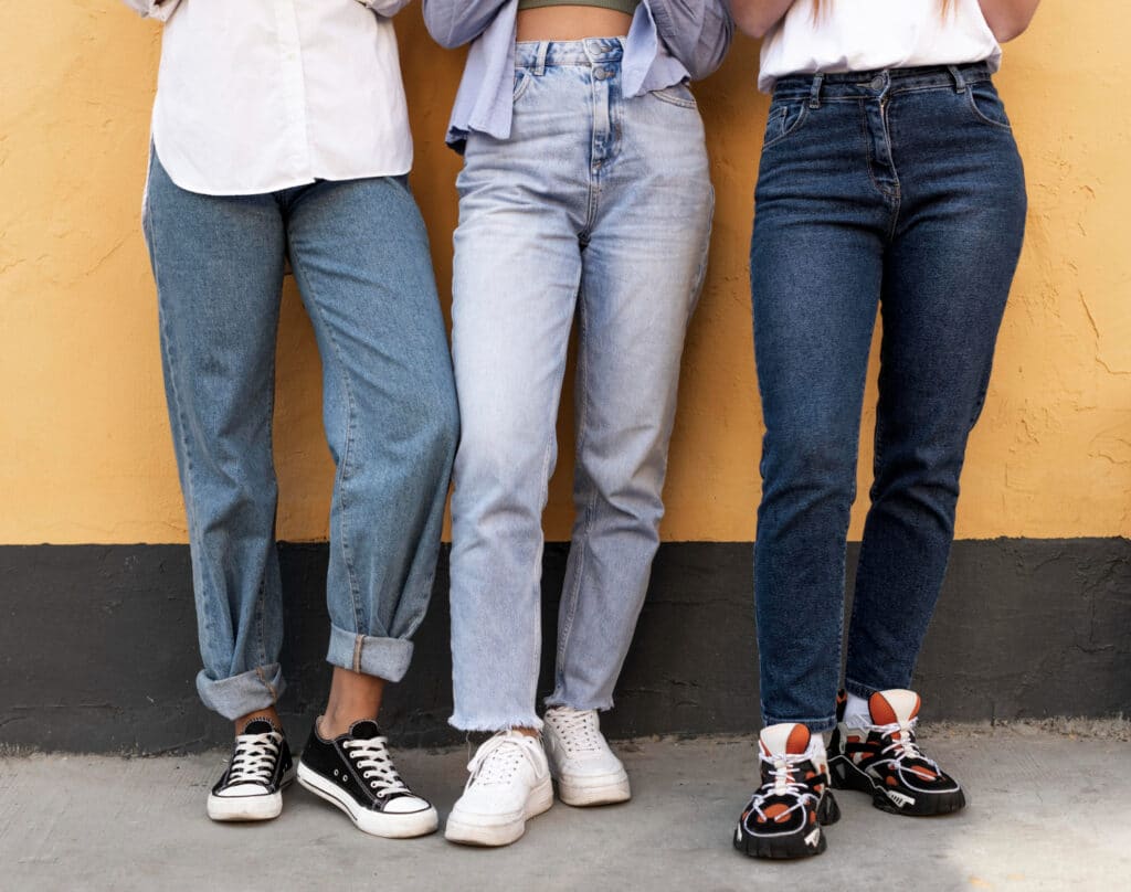 Vue de près de jambes de femmes portant des jeans de différents styles et de différentes nuances de bleu.