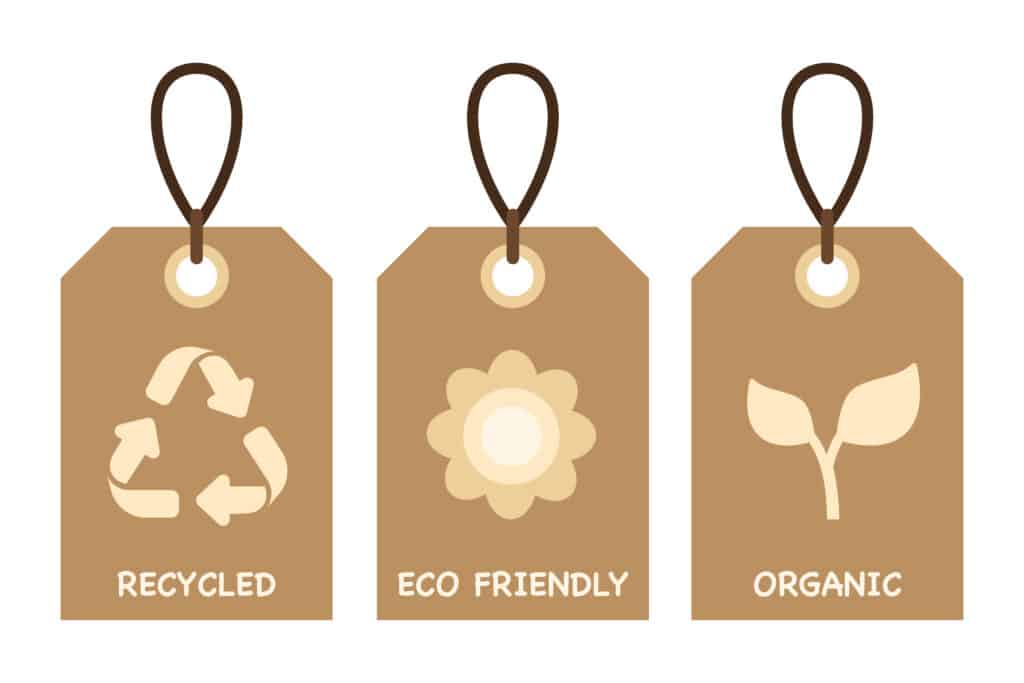 Trois étiquettes en carton marron avec des ficelles noirs. Sur les étiquettes sont marquées différents logos et inscriptions: recyclage, eéco friendly et organic.